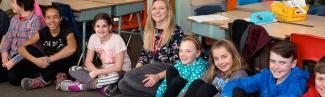 A student sits with children in a classroom